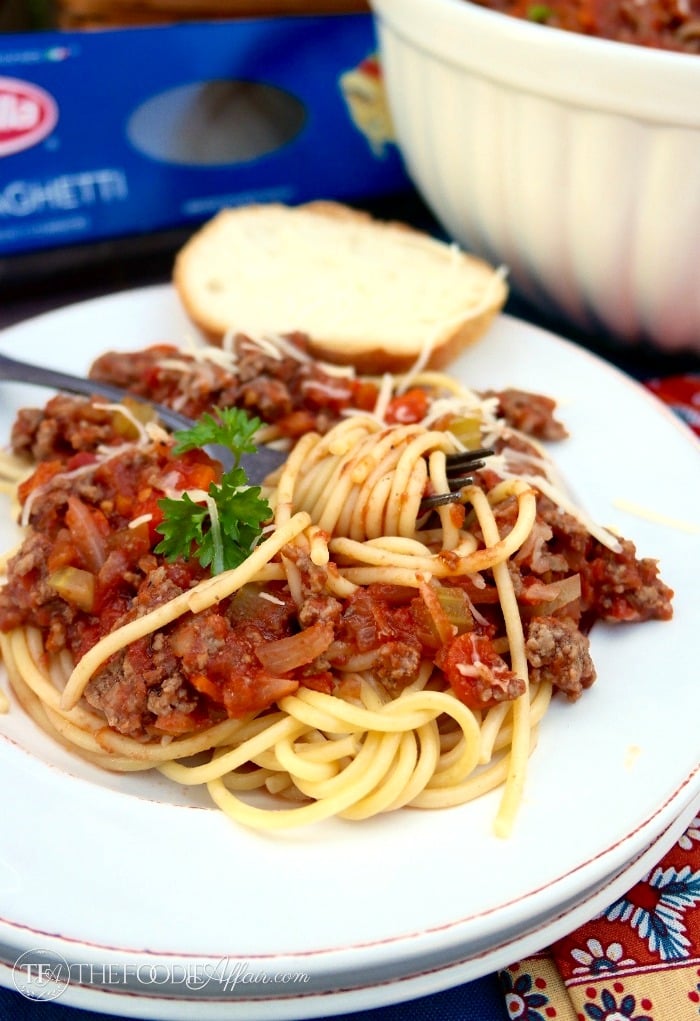 Spaghetti topped with meat sauce on a white plate