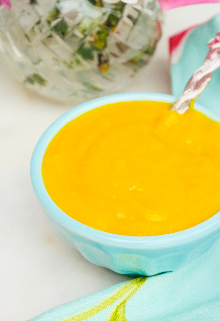 A teal bowl with mango pureed into a sauce.