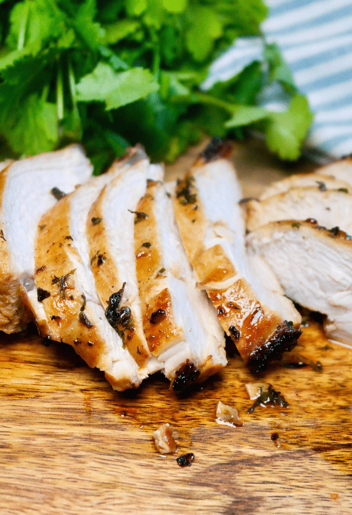 Sliced air fryer chicken breast with no breading on a cutting board.