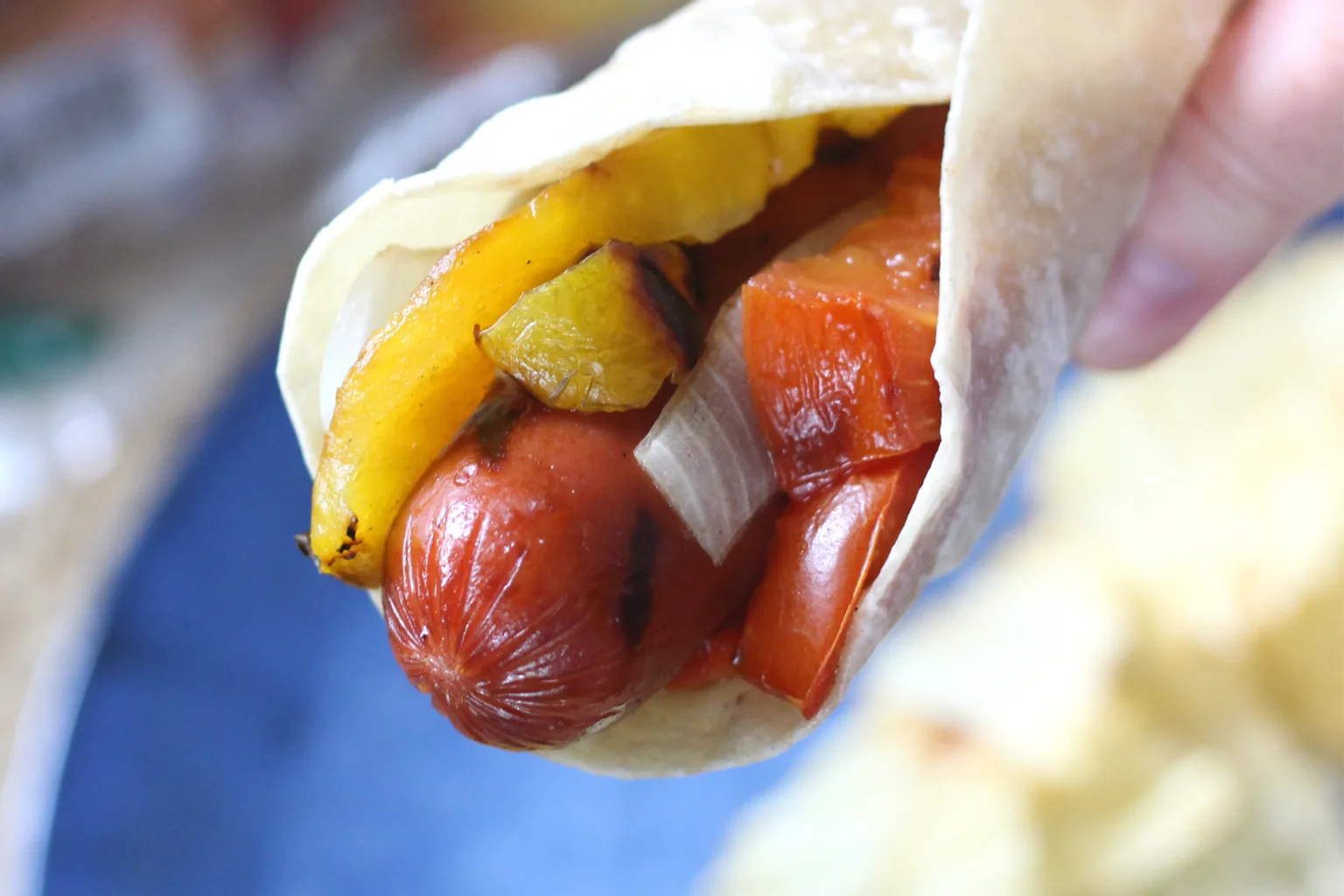 Grilled sausage wrapped in a tortilla with charred onions and peppers.